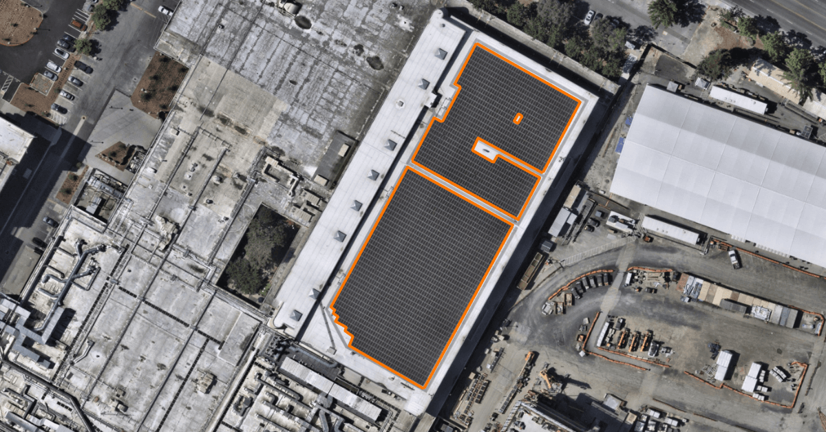 Satellite view of a flat commercial roof with two solar arrays outlined in orange